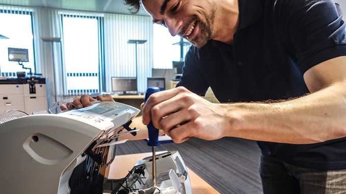 Technician working on Glory machine in bank.